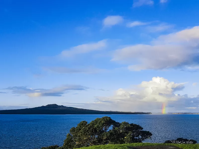 Colourful rainbow on the horizon next to Rangitoto Island